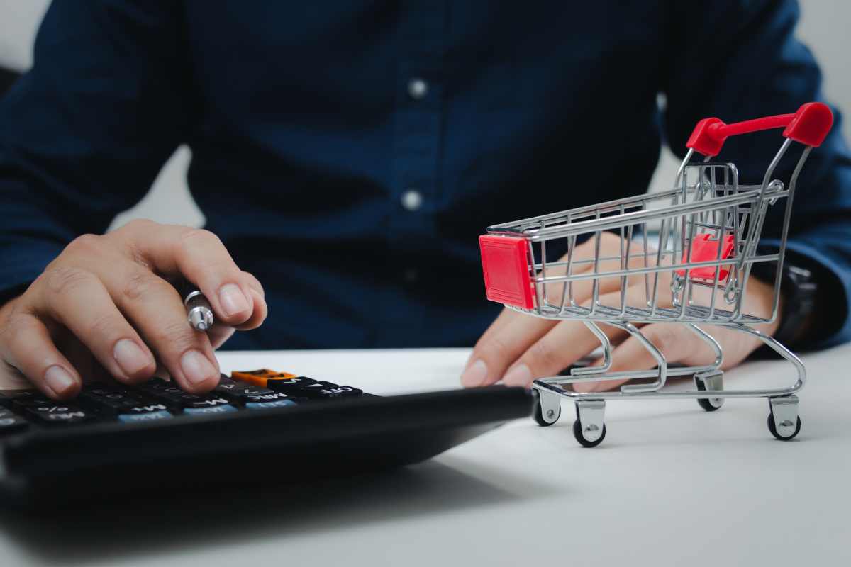 uomo con calcolatrice e carrello spesa